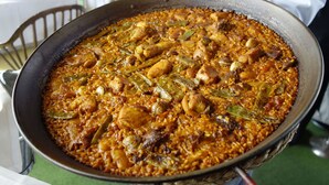A large pan filled with a dish containing rice, chicken, and vegetables. - Hostal La Masía (Villarreal)
