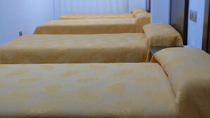 A row of beds with patterned bedding in a hotel room. - Hostal La Masía (Villarreal)