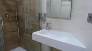 A modern bathroom with a glass shower enclosure, a white sink, and a mirror above it. - Hostal La Masía (Villarreal)