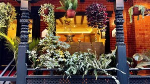 L’entrée d’un hôtel avec une façade en briques, des piliers décoratifs et des plantes suspendues.