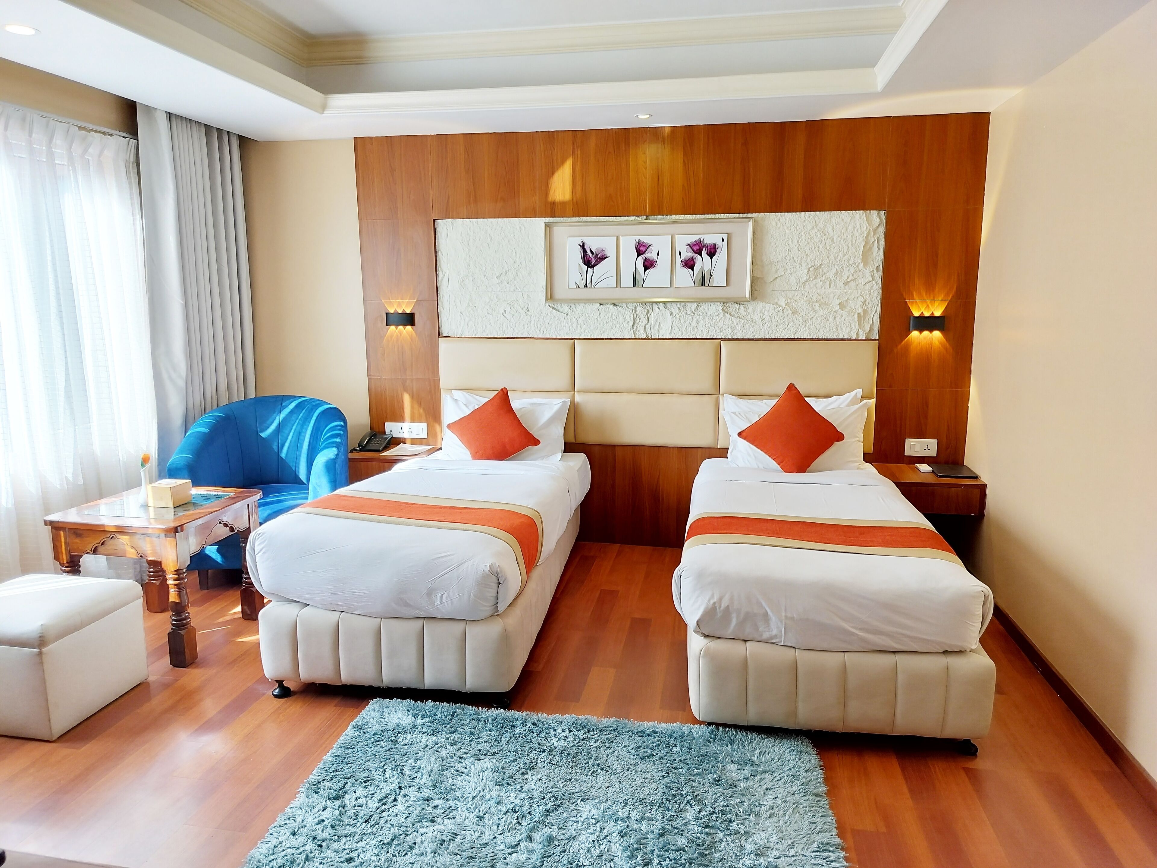 A hotel room with two beds, a sofa, a small table, and a blue rug.