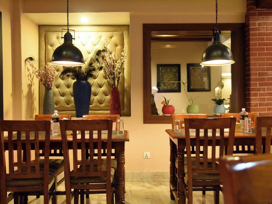 A dining area with wooden chairs and tables, a tufted headboard, and pendant lighting.
