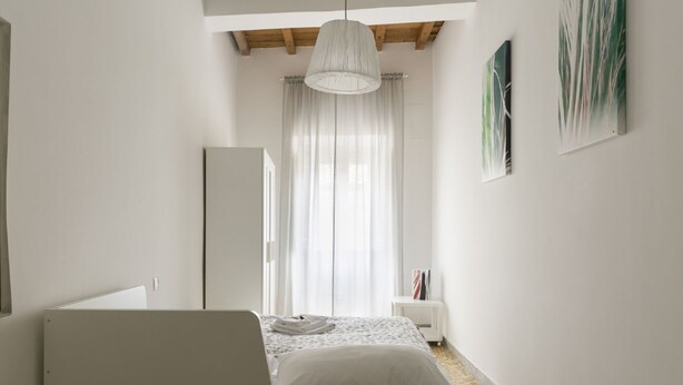Ein Schlafzimmer mit einem Bett, einem Nachttisch, einem Kleiderschrank und einer Deckenleuchte.