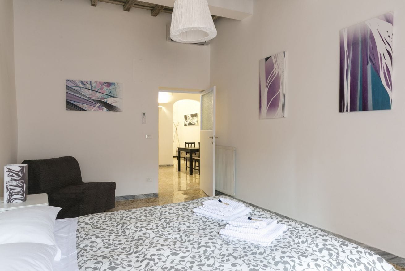 A bedroom with a bed, a chair, and artwork on the walls.