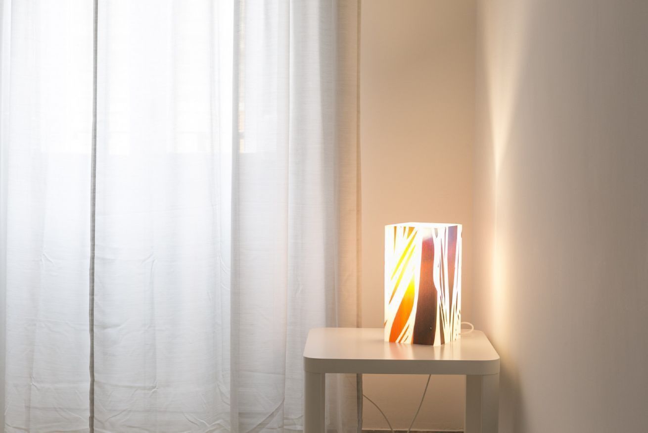 A room with a white table and a lamp with a colorful design.