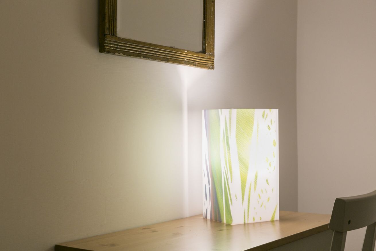 A room with a wooden table and a chair, a framed picture on the wall, and a large abstract artwork on the wall.