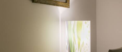 A room with a wooden table and a chair, a framed picture on the wall, and a large abstract artwork on the wall.