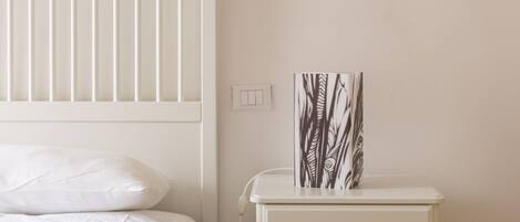 A bedroom with a bed, a nightstand, and a wall-mounted light switch.