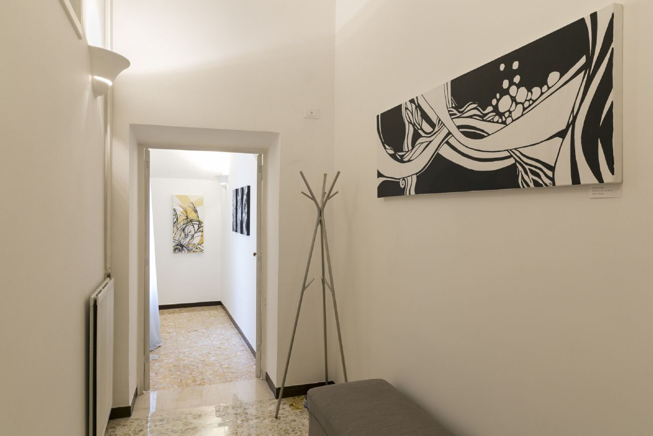 A hallway with a bench, a floor lamp, and a painting on the wall.