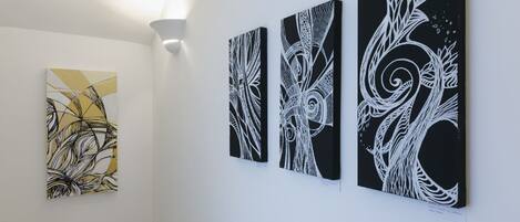Three abstract paintings on a white wall in a gallery setting.