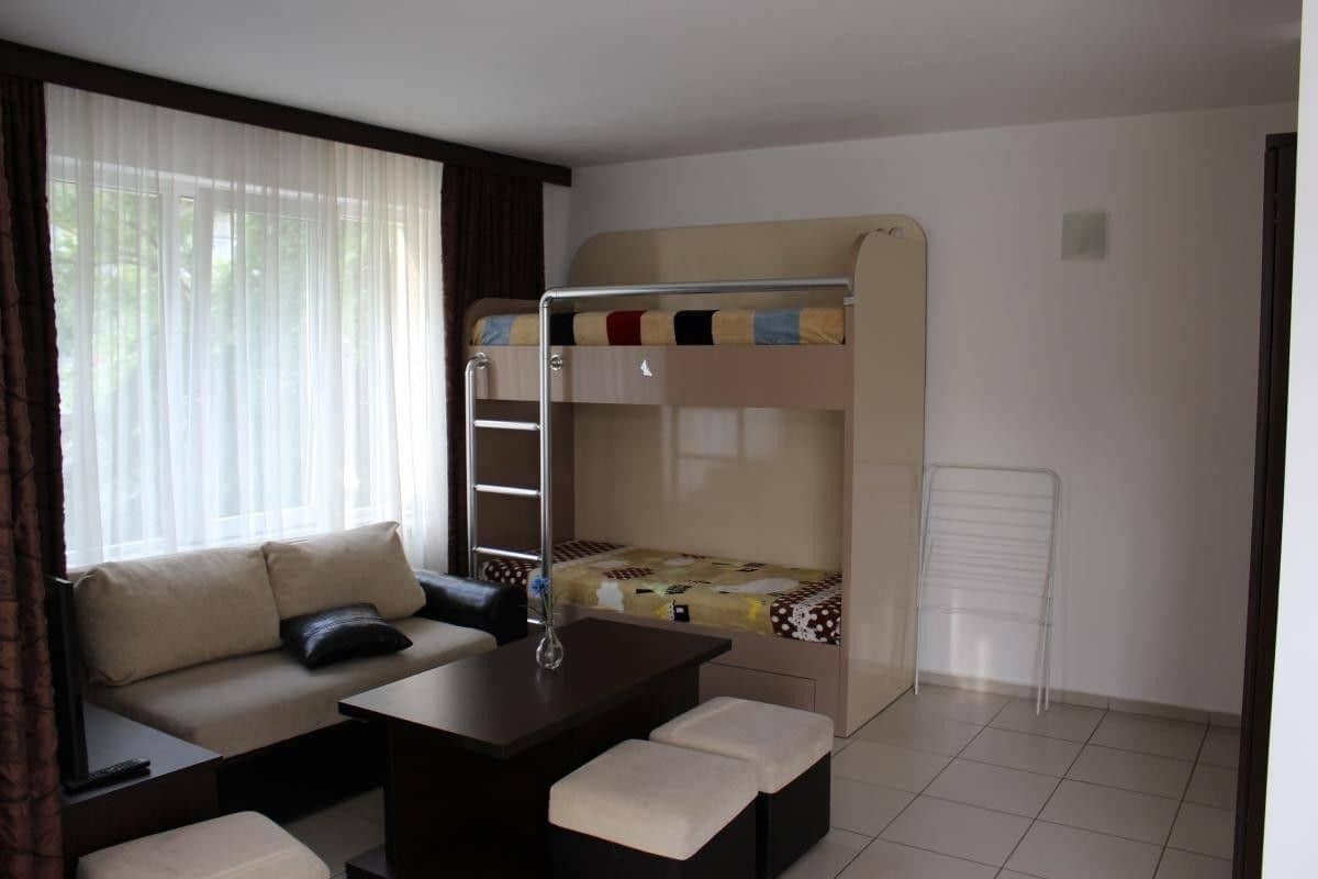 Ein Zimmer mit Etagenbett, einer Schlafcouch, einem kleinen Tisch und einem Heizkörper.
