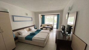 A hotel room with a bed, a desk with a TV, and a window with curtains. - Hotel Lilia 2 (Primorsko)