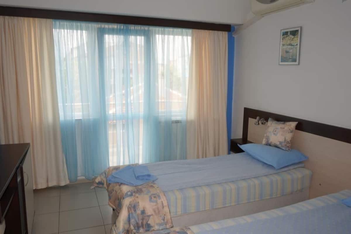 Ein Schlafzimmer mit zwei Betten, einem Schreibtisch und einem Fenster mit Vorhängen.