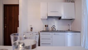 A compact kitchen with white cabinets, a stainless steel kettle, and a small countertop. - Rebecca's House (Verona)