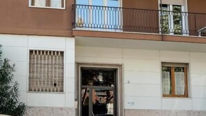 A multi-story residential building with balconies, a ground entrance, and parked cars. - Rebecca's House (Verona)