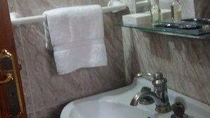 A bathroom with a white sink, a towel hanging on a rack, and a glass shelf with toiletries. - Sweet Azrou Holiday (Azrou)