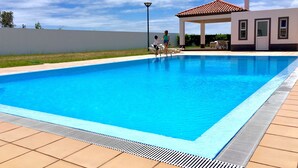 A rectangular swimming pool with a tiled deck surrounding it. - Casa do Ó (Ponta Delgada)