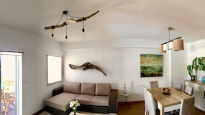 A modern living room with a sofa, dining table, and chairs, a chandelier, and a painting on the wall. - Casa do Ó (Ponta Delgada)