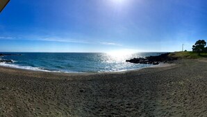 A beach with a clear sky, a rocky shoreline, and a few trees. - Casa do Ó (Ponta Delgada)
