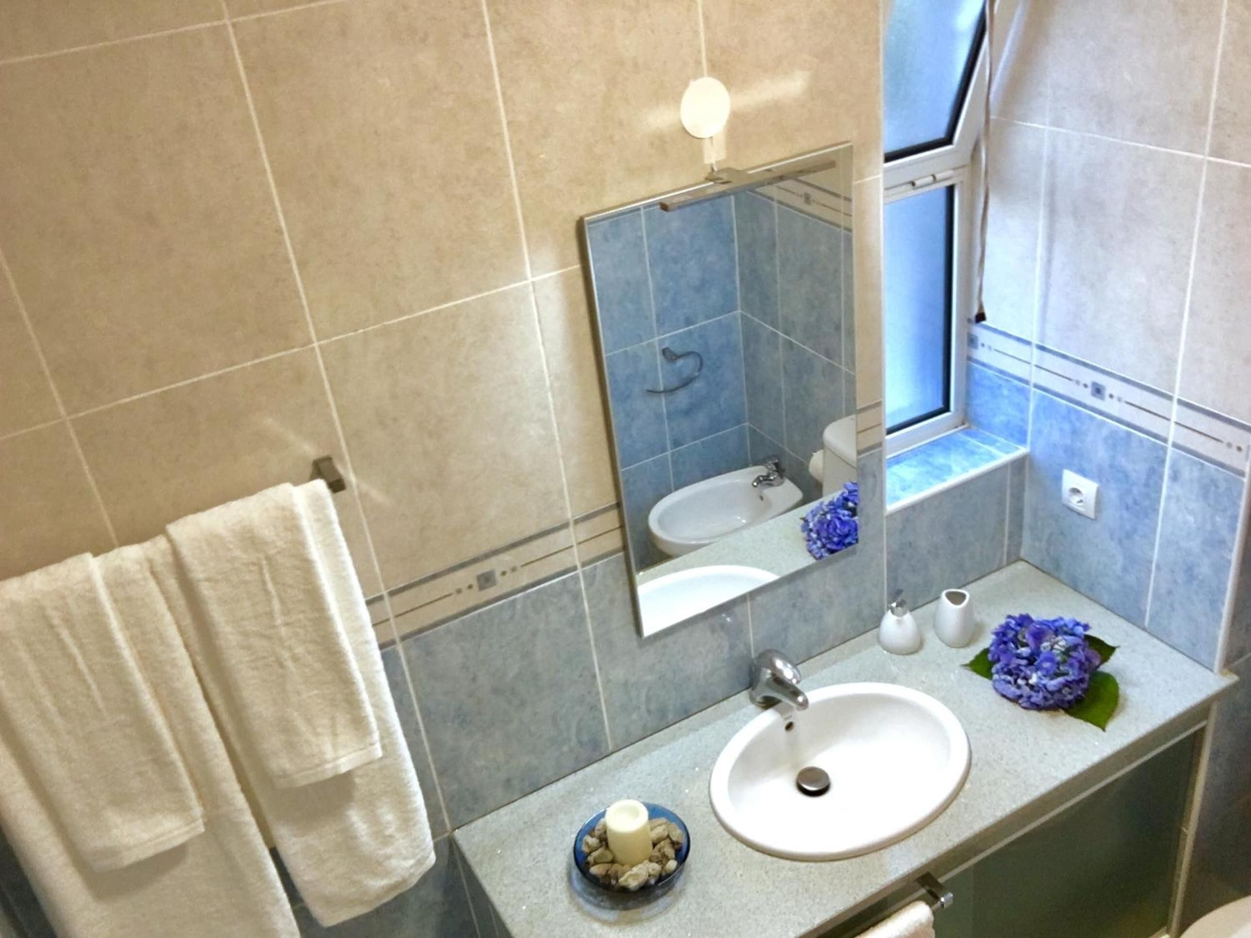 Un baño con un lavamanos blanco, un espejo, un perchero para toallas y un pequeño cuenco decorativo.