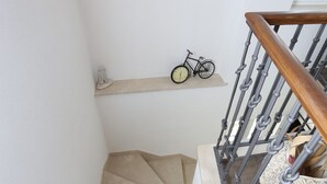 A staircase with a wooden handrail and a light fixture on the wall.