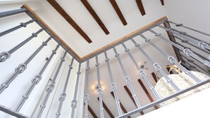 A staircase with metal railings and wooden beams, leading to a room with a white ceiling and a decorative white object.