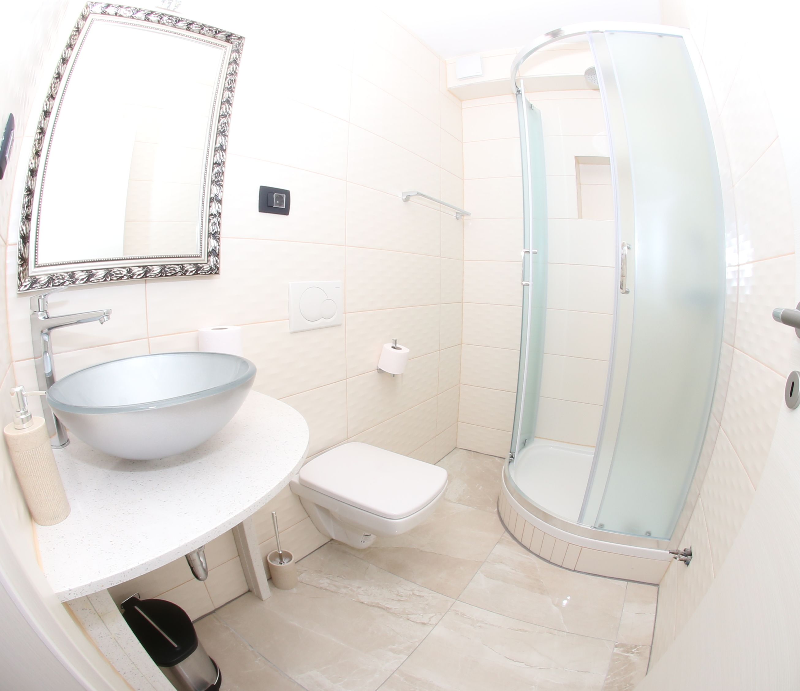 Un baño con un espejo grande, un lavabo, un inodoro y una ducha con mampara de vidrio.