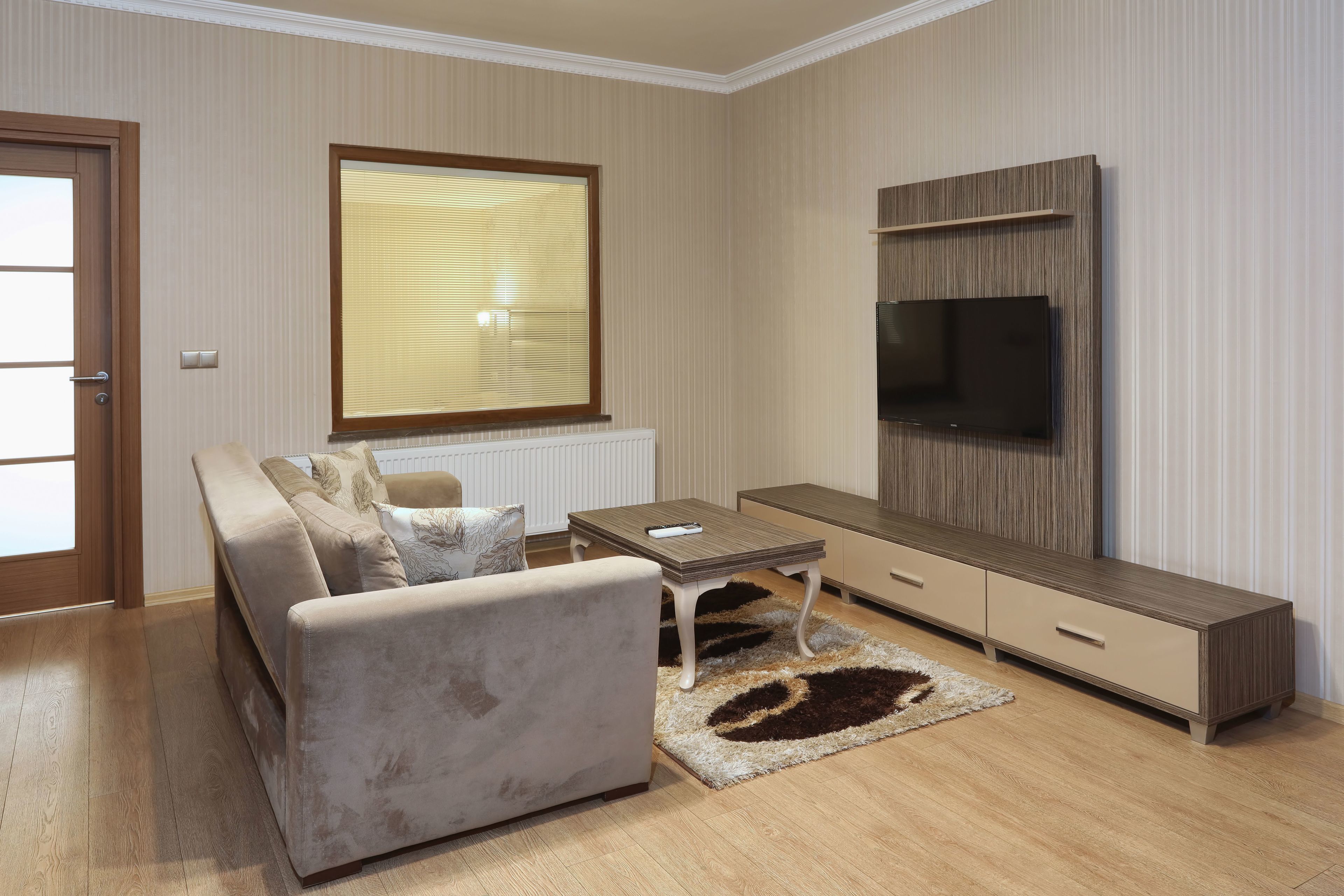 A modern living room with a sofa, coffee table, TV, and built-in shelving.
