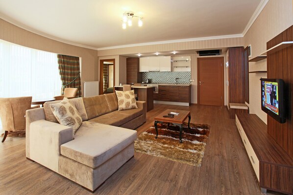 A modern living room with a sofa, a coffee table, and a TV mounted on the wall. - Balturk House Hotel (Izmit)