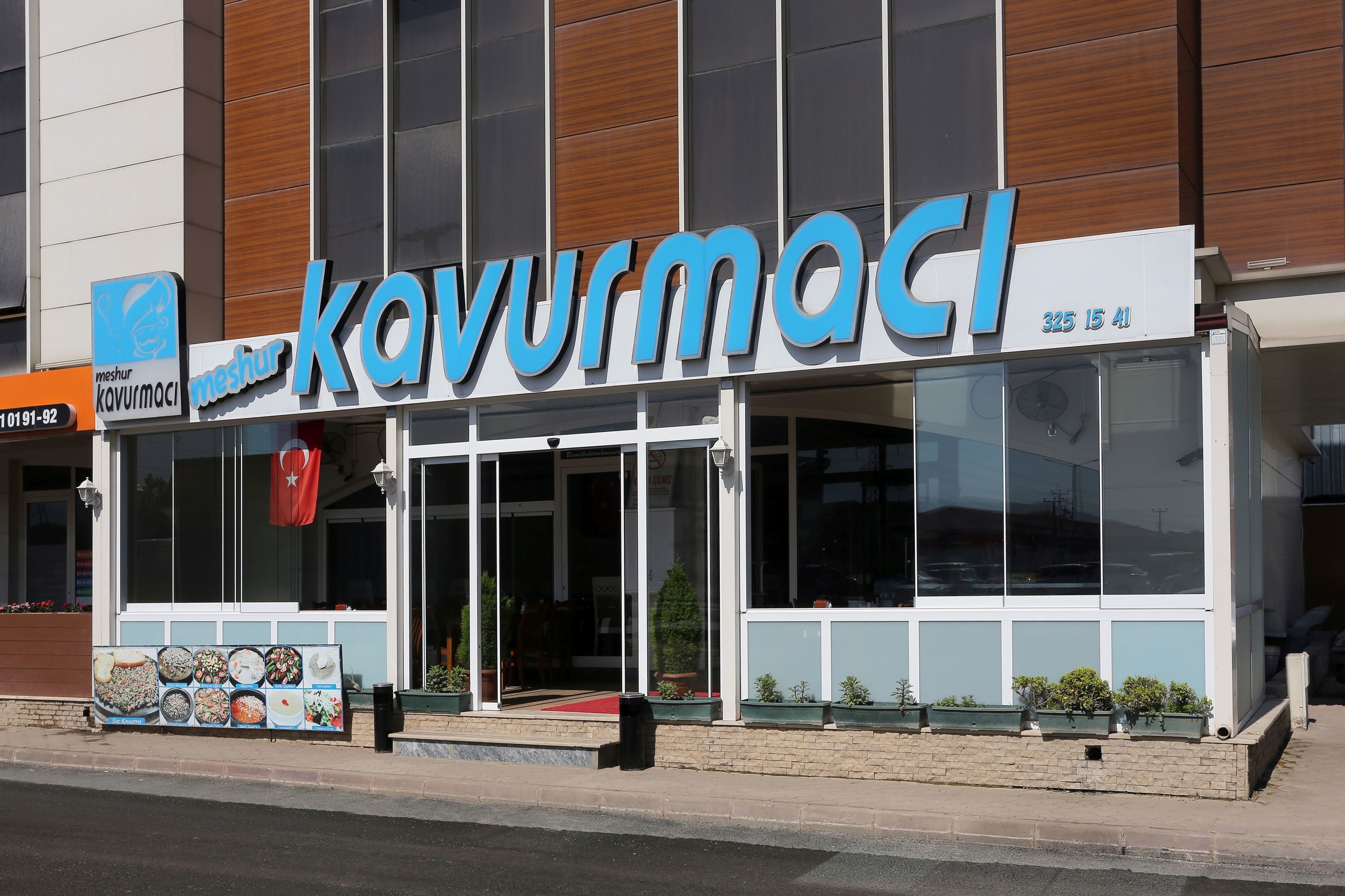 A modern building with a sign reading "KavurmaCI" and a contact number "325 15 41".