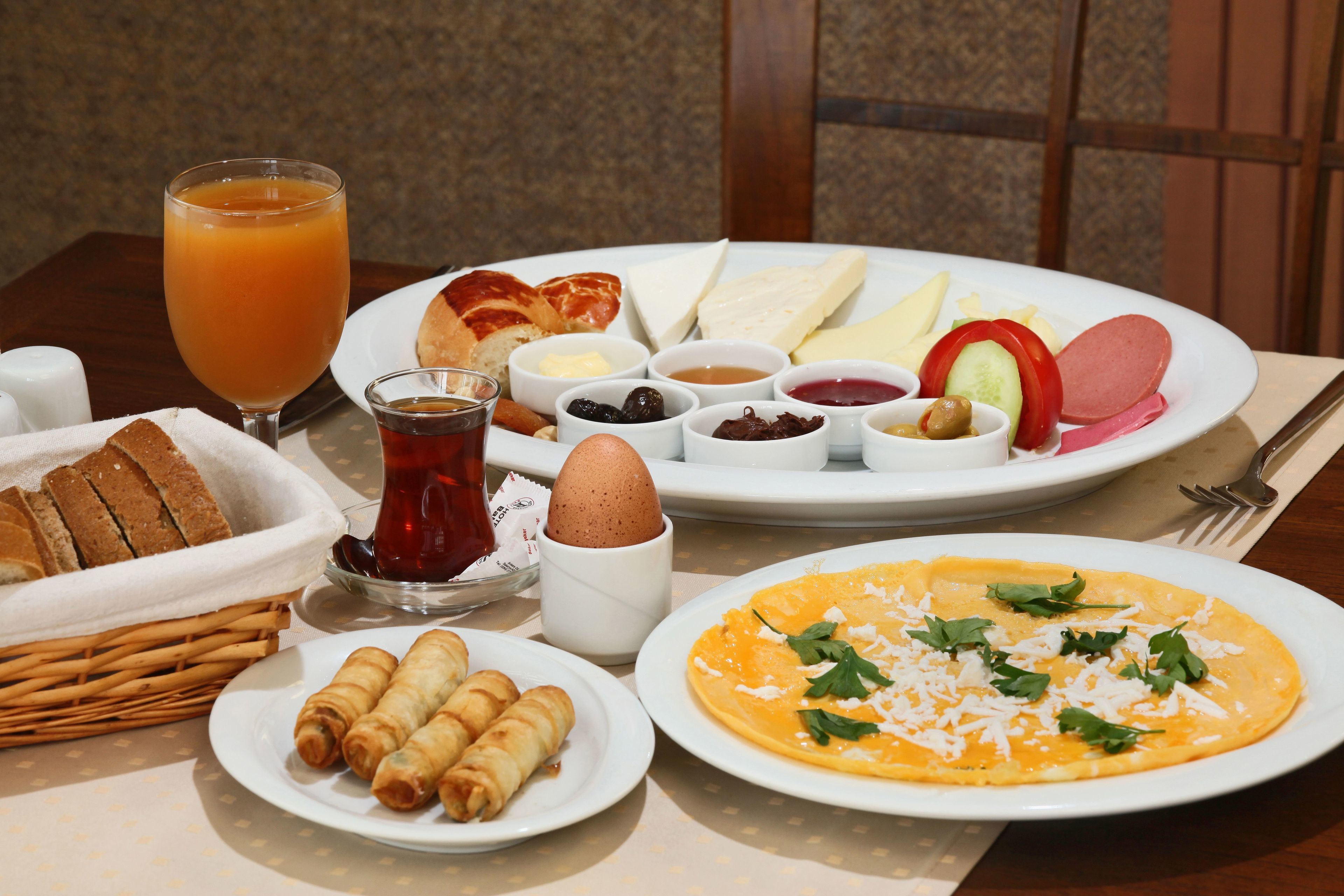 Un desayuno con tostadas, huevos, una fuente de queso y un vaso de zumo de naranja.