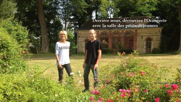 Two people standing in a garden with a building in the background. - Relais des Caillères (Saint-Pavace)