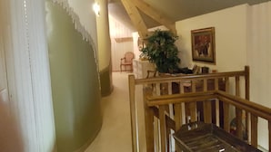 A staircase with wooden railings, a potted plant, and a painting on the wall. - Relais des Caillères (Saint-Pavace)