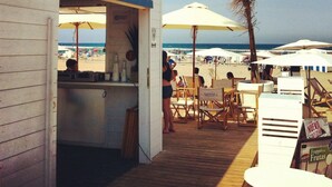 Un bar junto a la playa con terraza y sombrillas.
