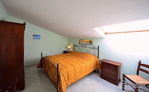 Ein Schlafzimmer mit einem Bett, einem Nachttisch, einer Kommode und einem Sessel.