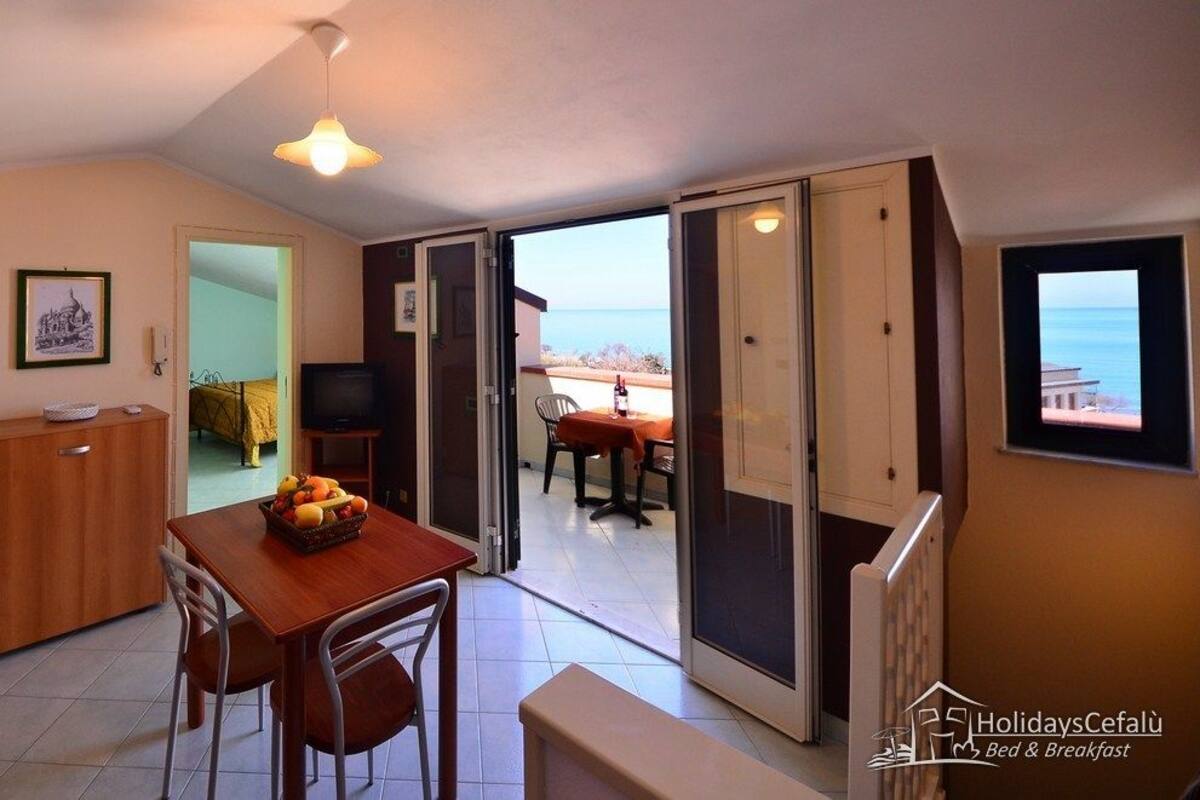 Una cocina compacta con una mesa y sillas, un mueble pequeño y un televisor.
