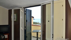 A room with a balcony, a television, and a table.