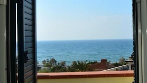 An open balcony with a view of the sea and a table with a chair.
