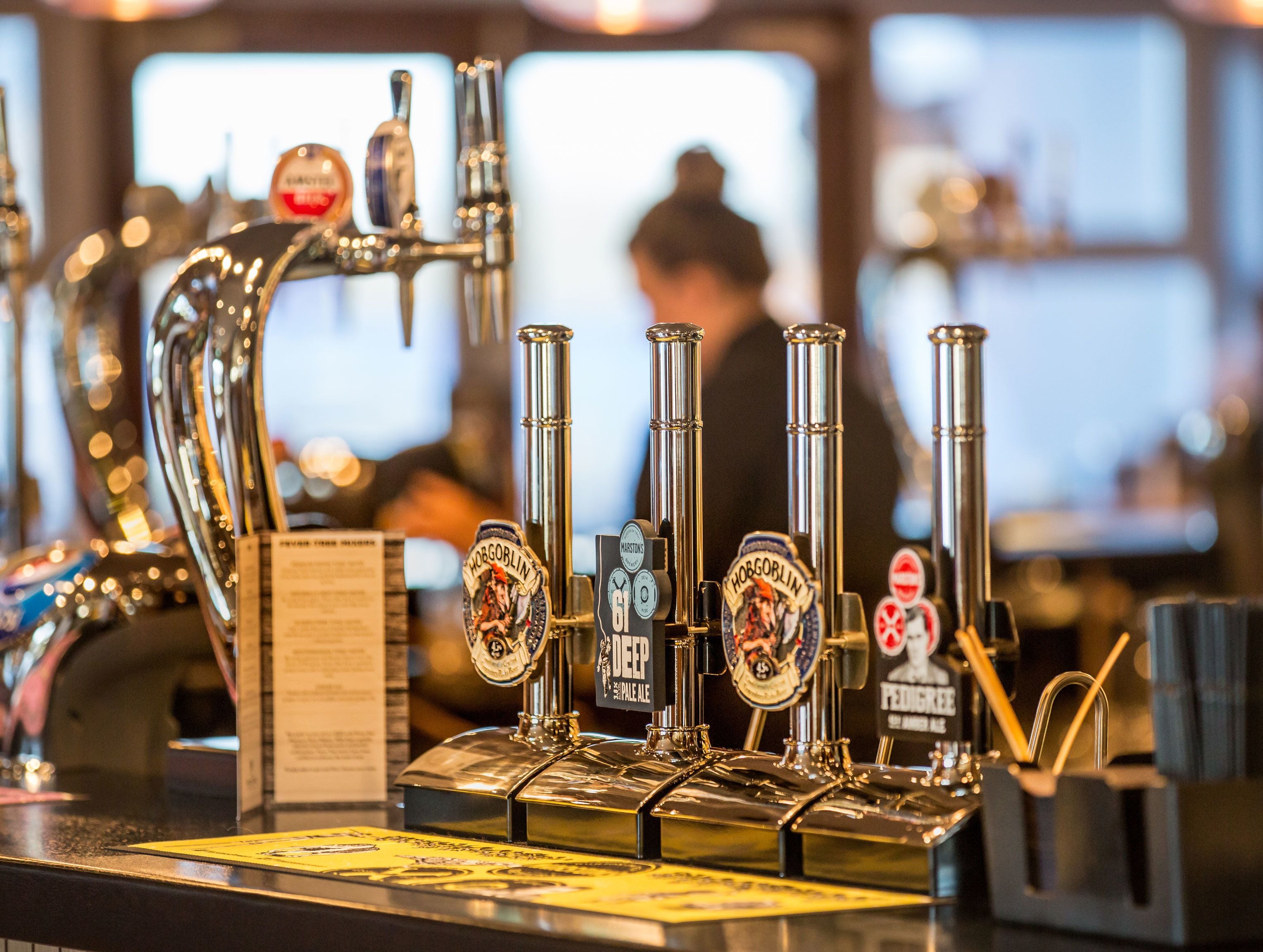 A tap system with multiple spouts and beer labels, including 'Hog's Head' and 'Pedigree'.