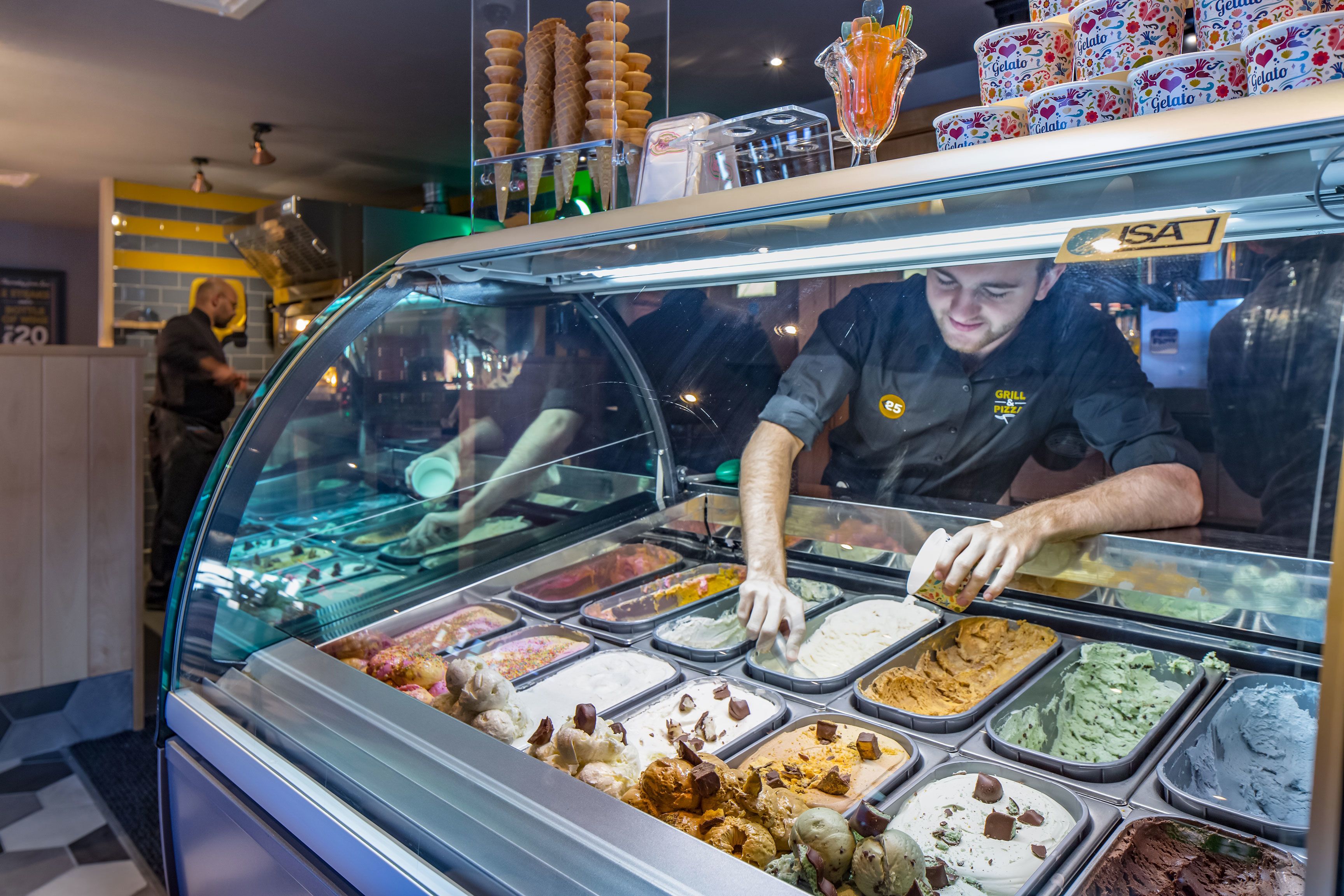 An ice cream parlor with multiple flavors displayed in a glass case.