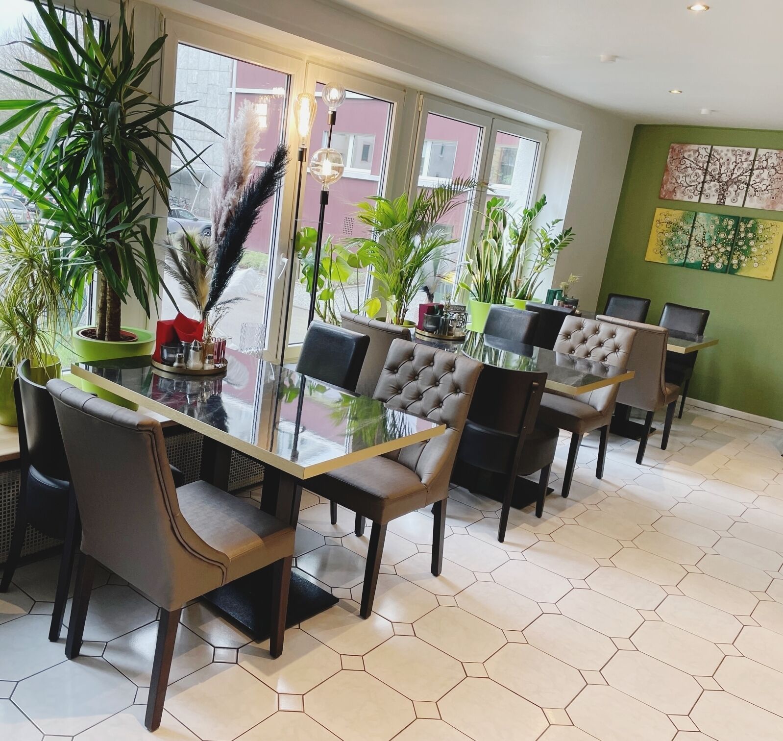A modern dining area with hexagonal tiled flooring, glass-top tables, and tufted leather chairs.