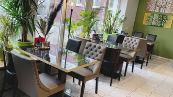 A modern dining area with hexagonal tiled flooring, glass-top tables, and tufted leather chairs.