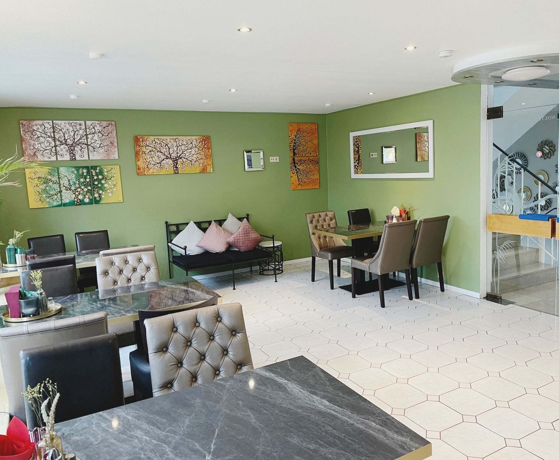 A spacious living area with a dining table, sofa, and chairs, a glass coffee table, and artwork on the walls.