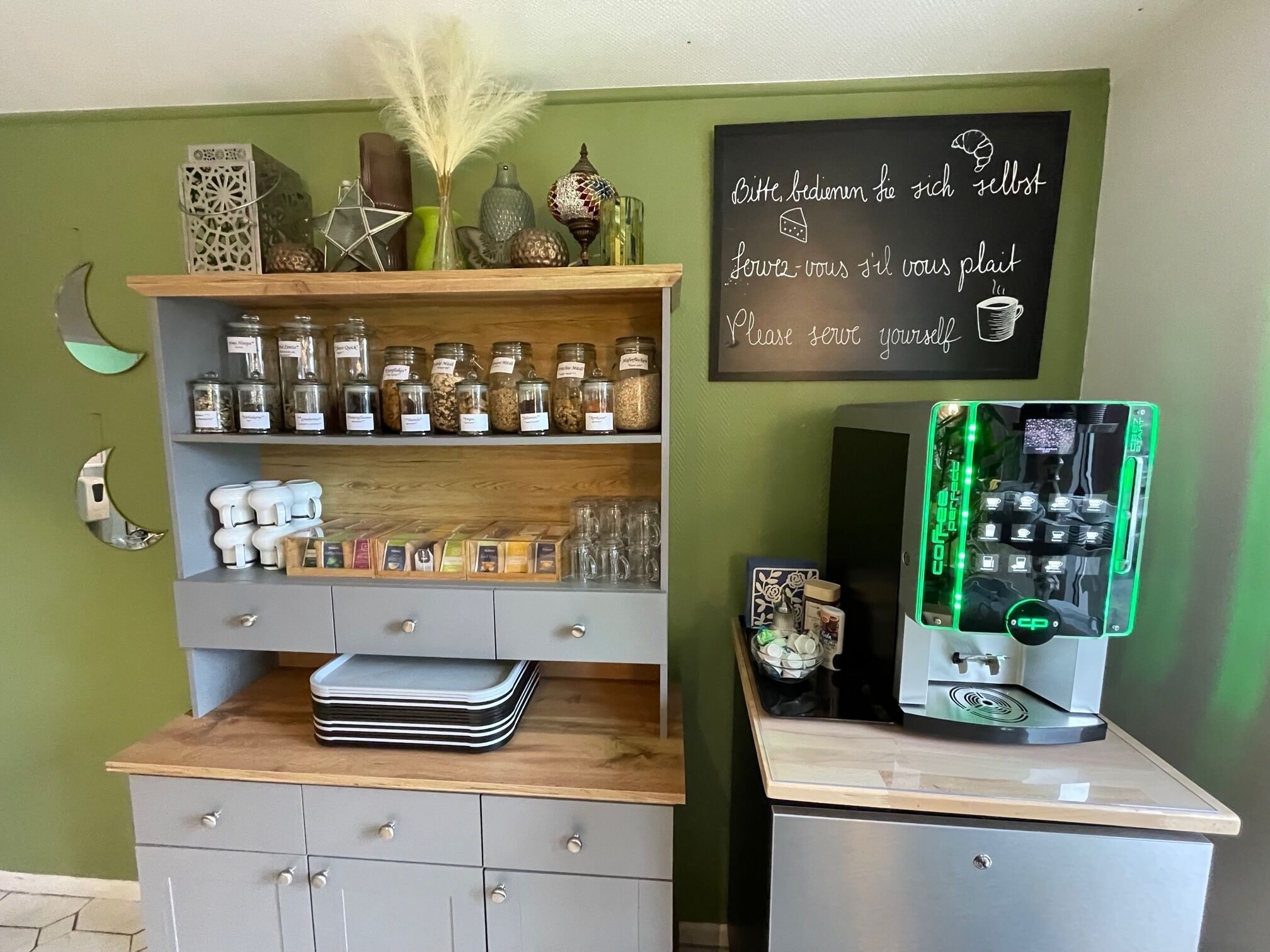 Una encimera de cocina con una cafetera, frascos de especias y una pizarra con un mensaje.