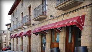 A row of stone buildings with red awnings and wooden doors, each labeled "BAR BODEGÓN". - Antiguo Casino de los Arribes (Fermoselle)