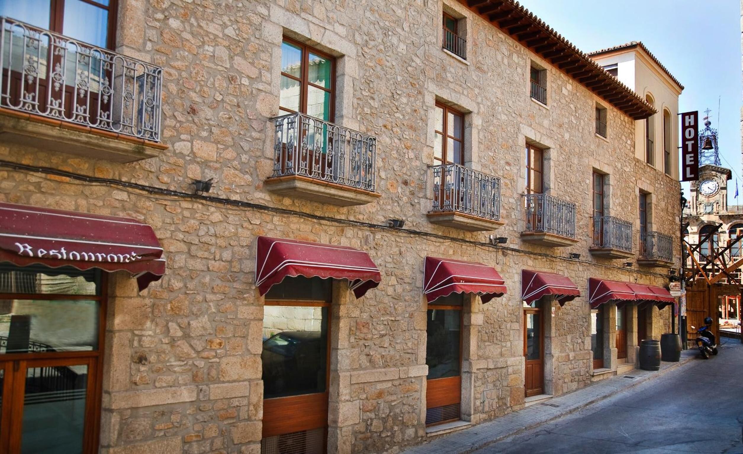 Un edificio de piedra con varios balcones y toldos, presumiblemente un hotel o restaurante.