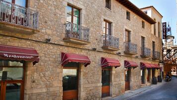 Un edificio de piedra con varios balcones y toldos, presumiblemente un hotel o restaurante.