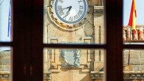 A clock tower with Roman numerals and a flag. - Antiguo Casino de los Arribes (Fermoselle)