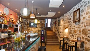 A bar area with a stone wall, wooden bar counter, and stools. There is a staircase leading to an upper level. - Antiguo Casino de los Arribes (Fermoselle)