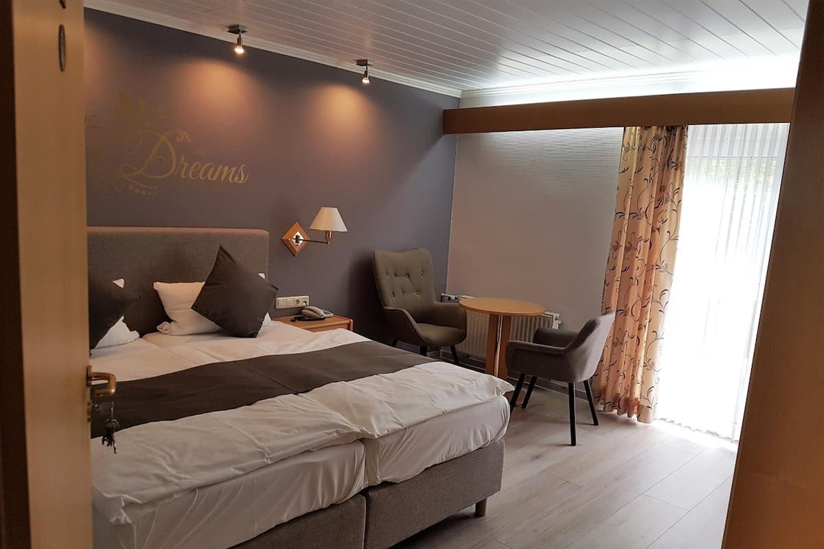 Quarto de hotel moderno com uma cama grande, uma escrivaninha e uma cadeira.